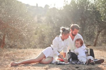 Happy family enjoying a picnic in an olive grove under the sun. Perfect for lifestyle and outdoor themes.