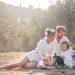 Happy family enjoying a picnic in an olive grove under the sun. Perfect for lifestyle and outdoor themes.