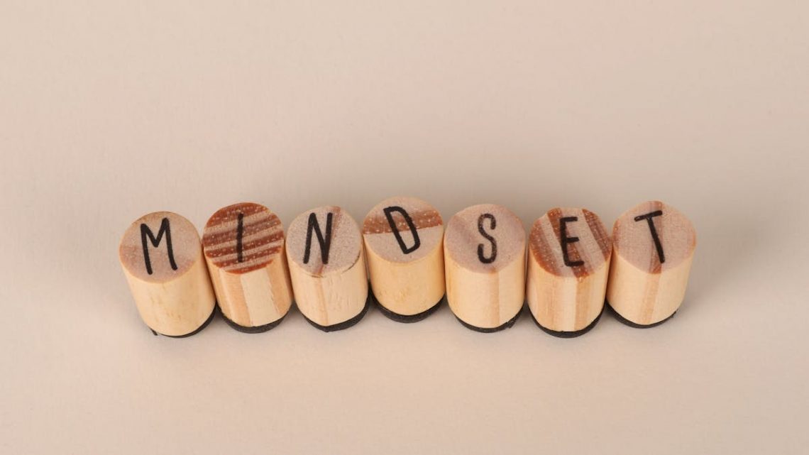 Wooden letter stamps spelling 'Mindset' on a simple beige background, conveying focus and positive thinking.