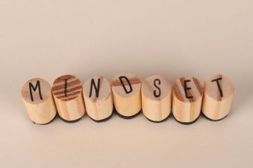 Wooden letter stamps spelling 'Mindset' on a simple beige background, conveying focus and positive thinking.