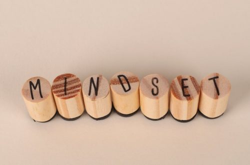 Wooden letter stamps spelling 'Mindset' on a simple beige background, conveying focus and positive thinking.